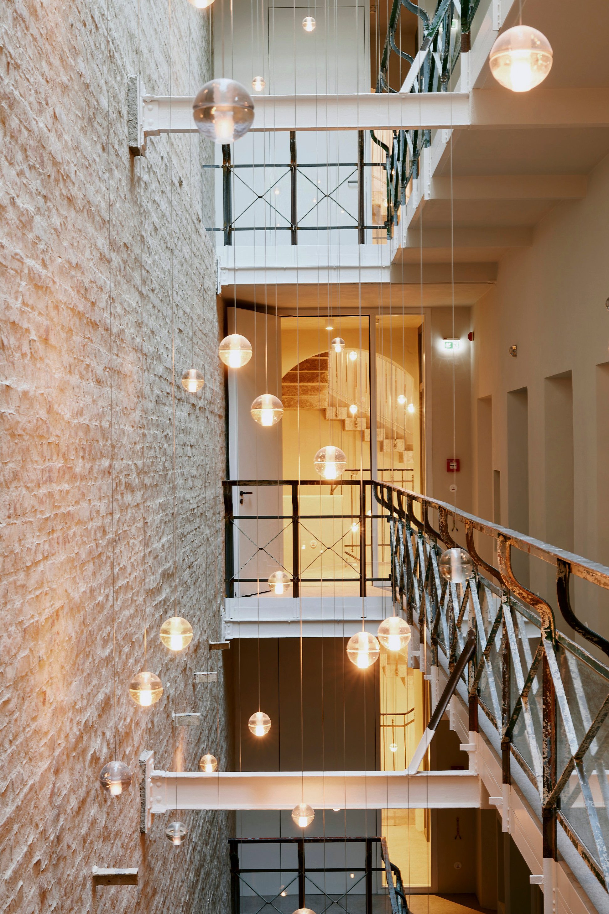 Old and new remain distinctly visible: in Wilmina's atrium, exposed brickwork and preserved metal railings meet an installation of glass pendant lights.