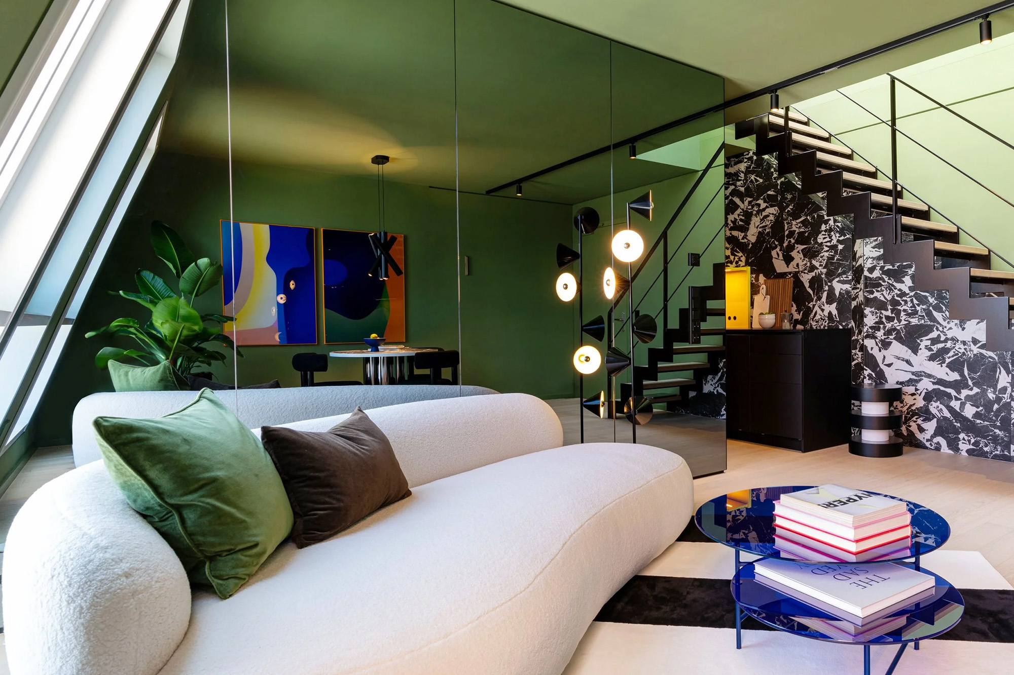 An open living space with mirrored sightlines, color, and sculptural lighting.