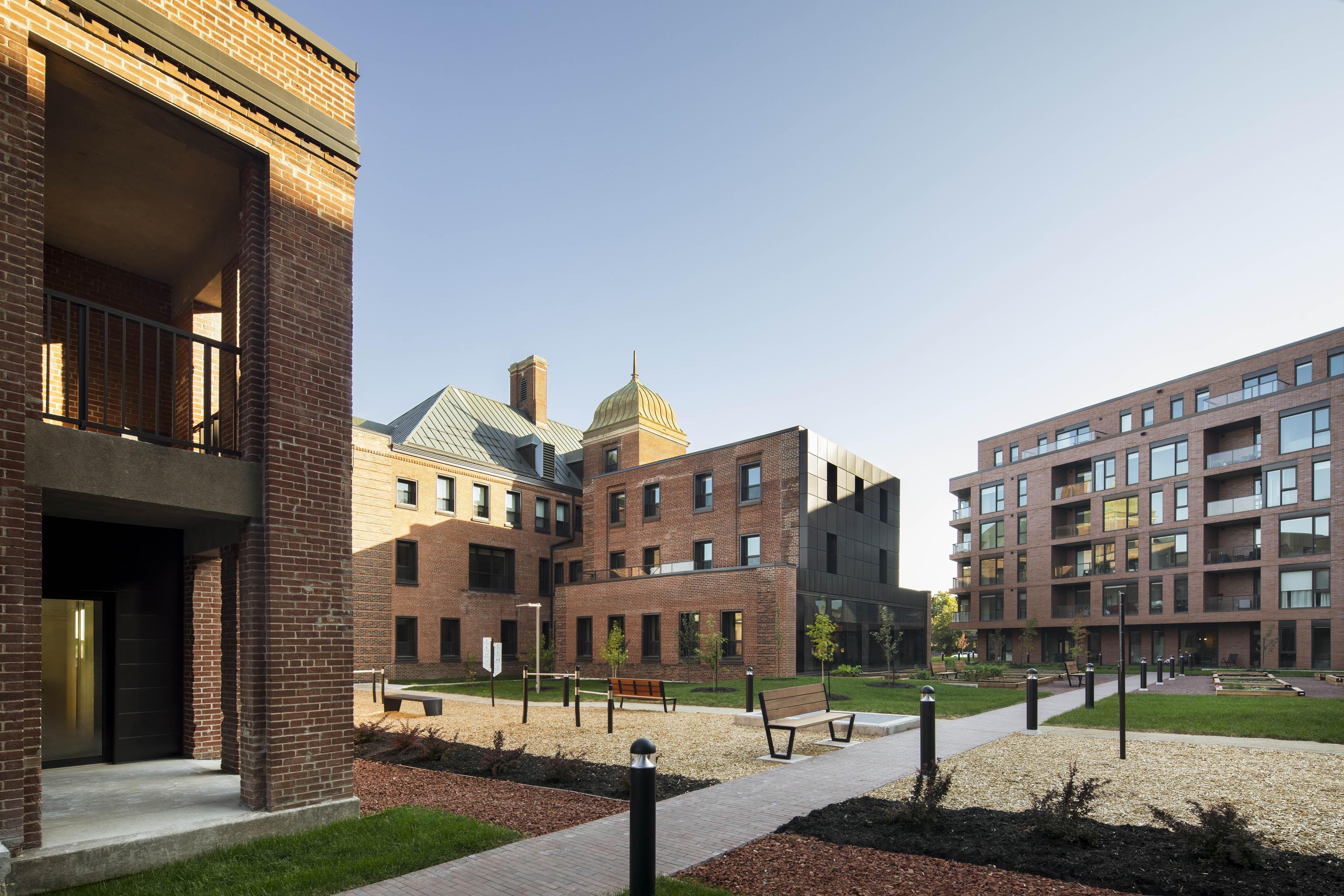 No attempt at historic imitation: the new building references the material and colour of the existing structure while maintaining a contemporary architectural language.