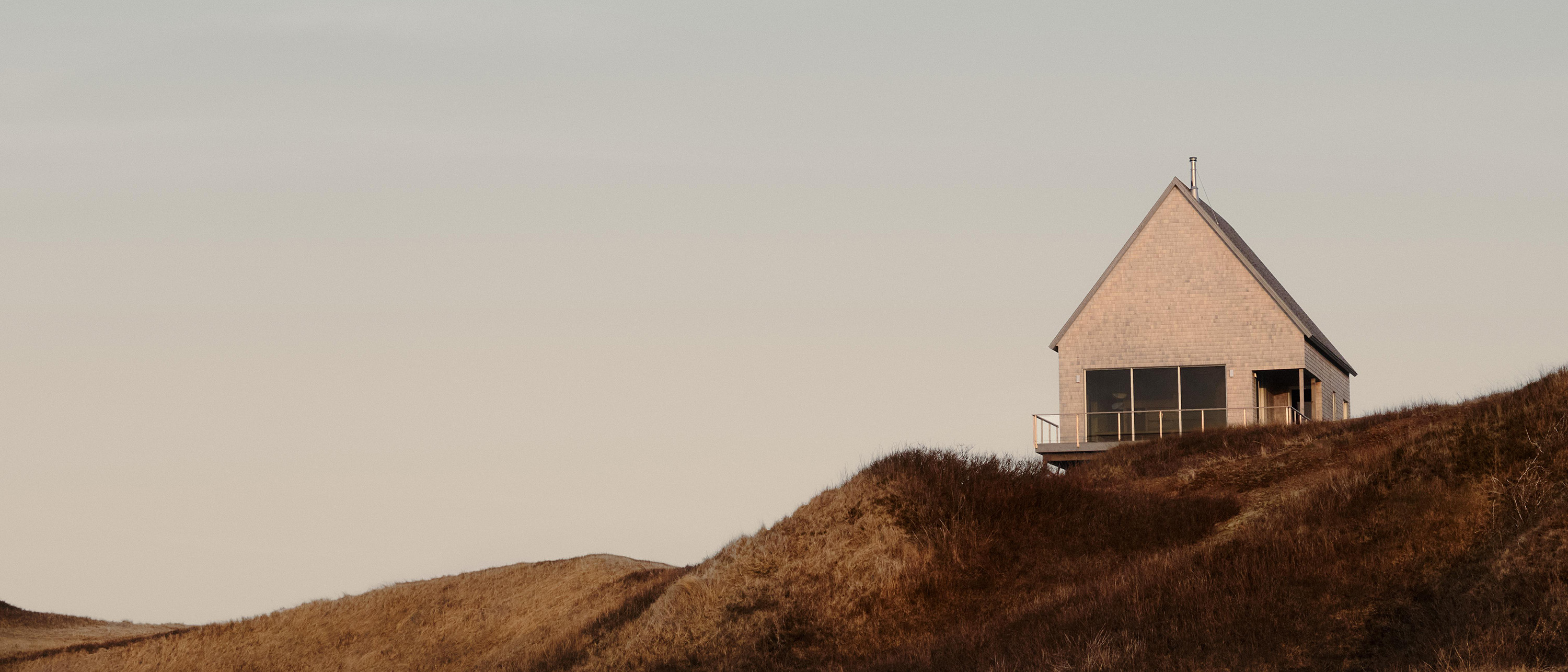 Set at the edge of the plateau, Magdalen House appears as a compact gabled volume. Its cedar-shingle envelope adopts the scale and silhouette of the islands’ vernacular architecture. Photography: Alex Lesage and Nicolas Lapierre.