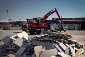 Recycled wood at Lenocart’s site near Milan, where a material handler moves wood-based panel offcuts for further processing.