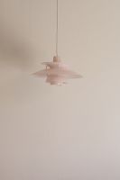 Pink Louis Poulsen PH 5 pendant lamp against a light wall.