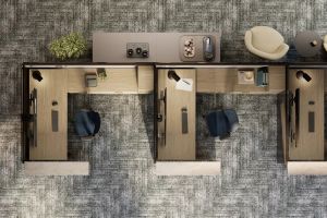 Top view of several furnished Steelcase workstations with desks, office chairs, task lights, storage and patterned carpet flooring.