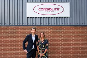 Tommy Stranden of Glamox and Lyndsey Eriksson of Consolite standing outside the Consolite building beneath the company sign.